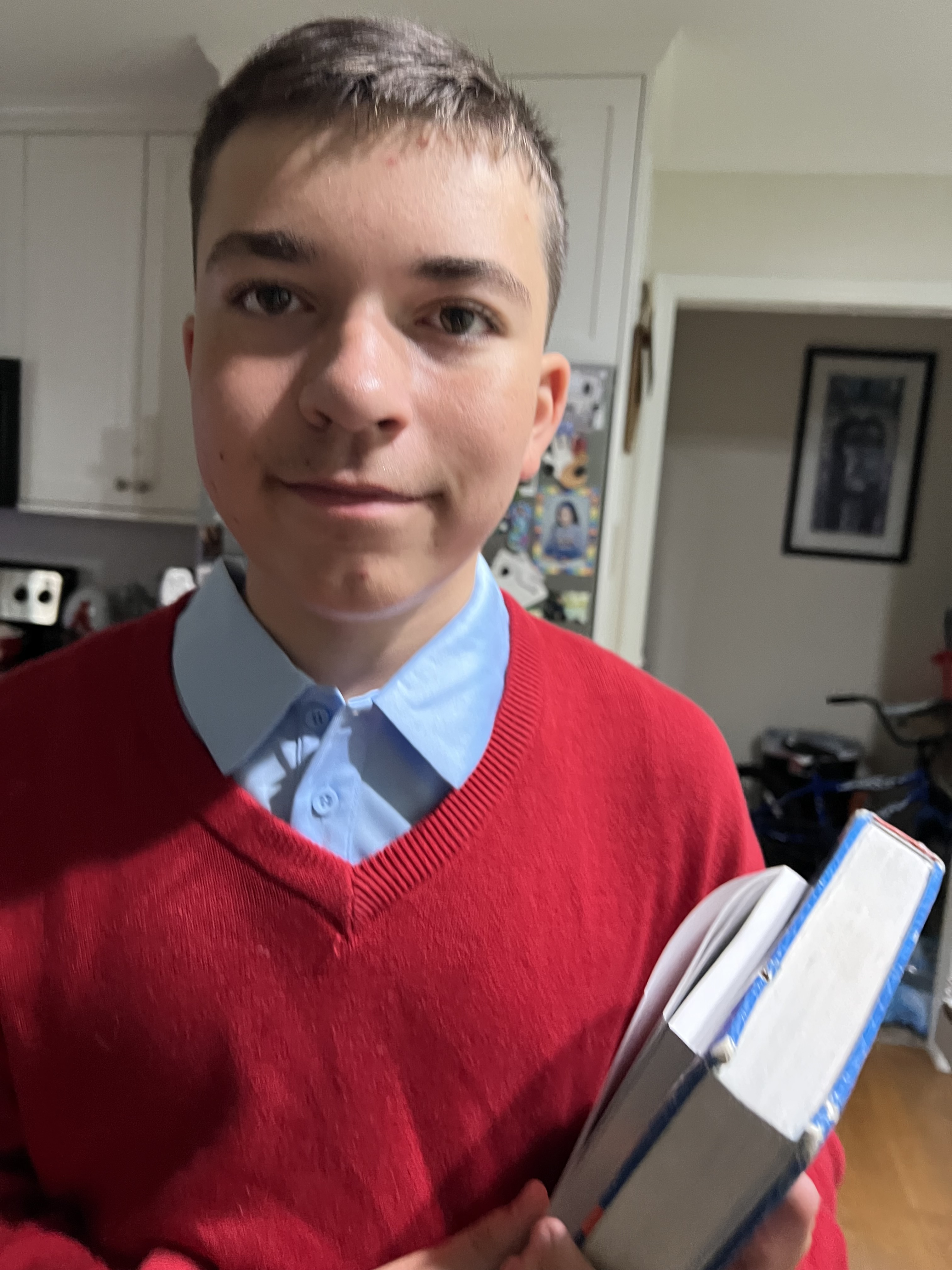 Kingston preparing for academics, holding books in a red sweater