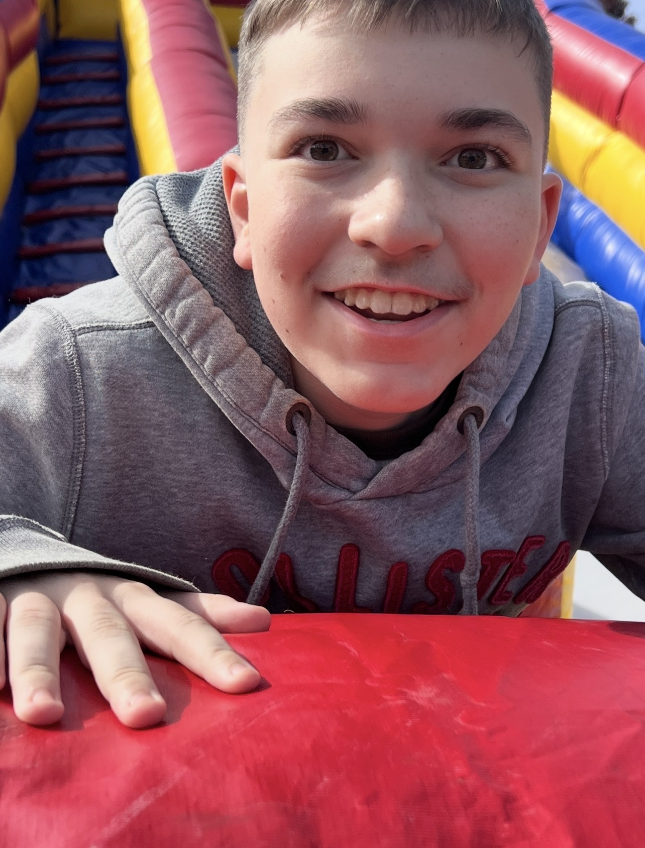 Kingston grinning while sliding on an inflatable bounce house
